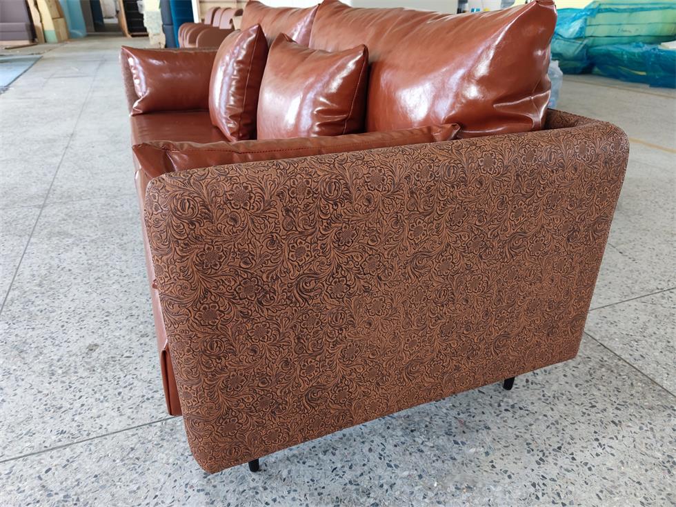 Close-up of embossed patterned side panels on a luxurious brown leather sofa, highlighting intricate detailing.