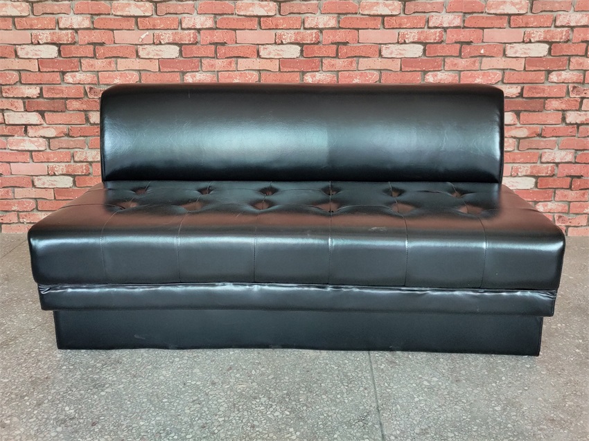 A wide view of the black faux leather KTV sofa, highlighting its smooth tufted seat and sleek backrest