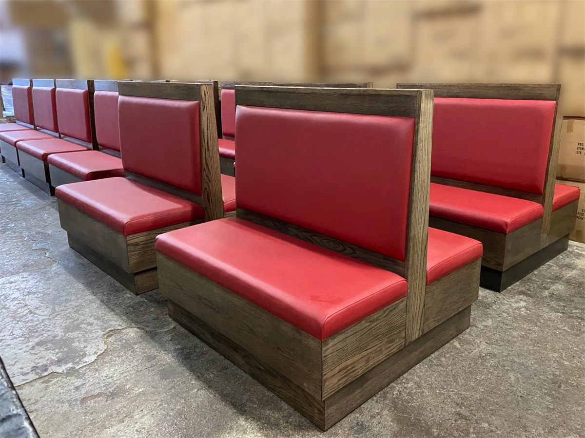 Commercial double-sided red leather corner booth seating with a wooden frame for restaurant use.