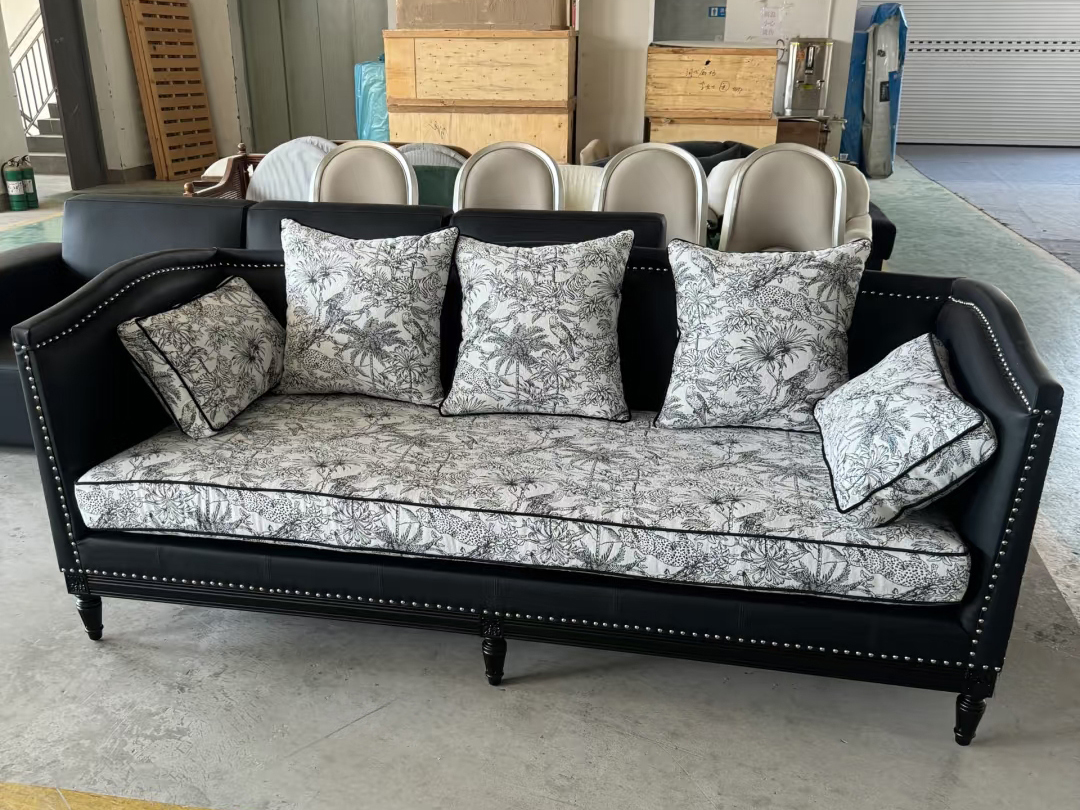 Three-seater couch with tufted armrests and monochrome tropical cushions